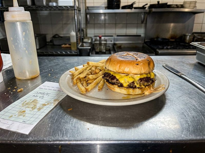 A quick phone photo of a burger and fries on a stainless kitchen pass before DishReady